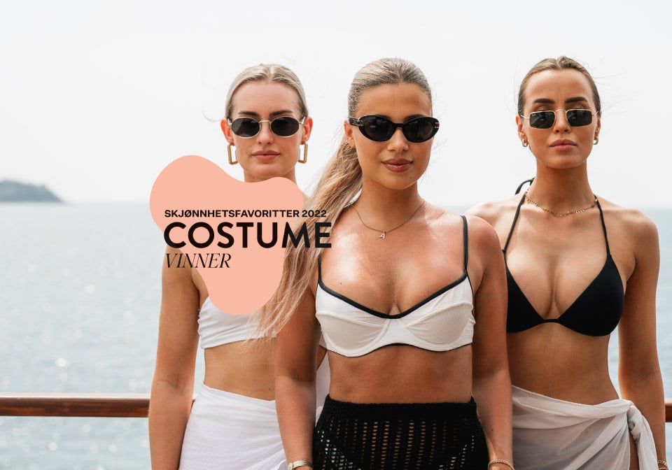 Three tan girls in bikinis posing for Betakaroten Gold with the Costume logo
